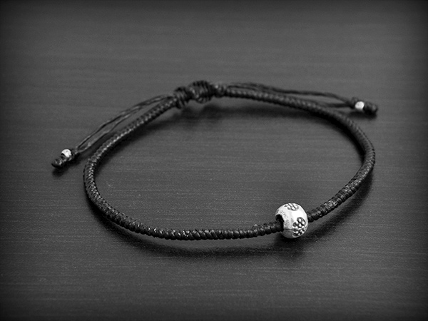Bracelet réglable en cordelière de lin (fil poissé) très résistant avec au centre une perle ronde...