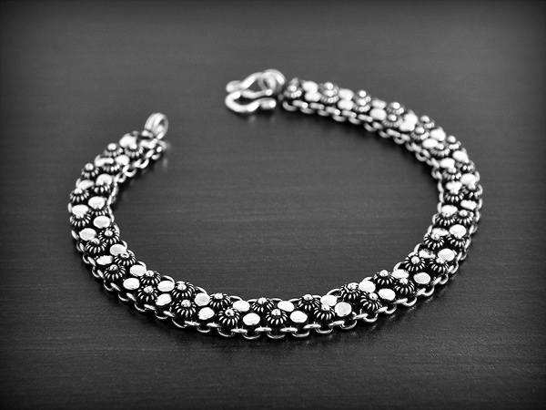 Joli bracelet en argent avec une maille décorée de deux rangées de petites fleurs de frangipanier...