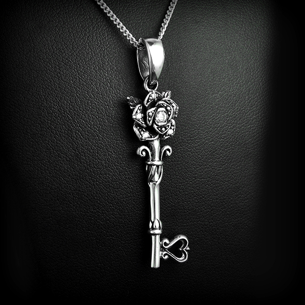 Très beau pendentif d'une clef en argent, surmontée d'une rose décorée d'un zirconium blanc. Au...