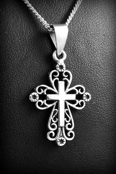 Joli pendentif en argent d'une petite croix parée d'ornements ajourés (h:25mm).