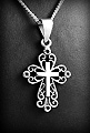 Joli pendentif en argent d'une petite croix parée d'ornements ajourés (h:25mm).