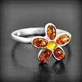 Bague en argent d'une jolie fleur dont les pétales sont serties d'une perle d'ambre cognac et le...