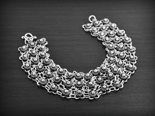 Superbe bracelet en argent composé d'une maille aérée en 3 rangées de petites fleurs (largeur:22mm).