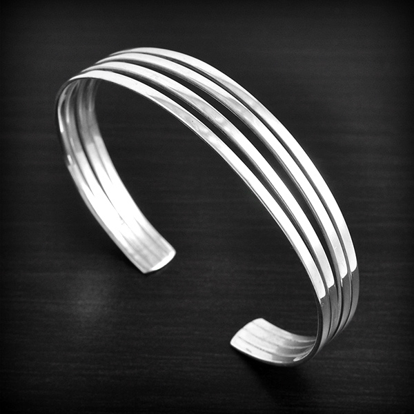 Bracelet rigide ouvert en argent constitué de 4 lamelles espacées se resserrant aux extrémités...
