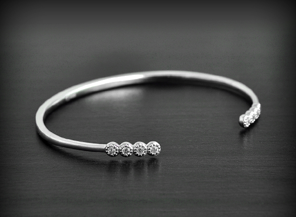 Ravissant bracelet rigide en argent orné aux deux extrémités de quatre zirconiums blancs irisés...