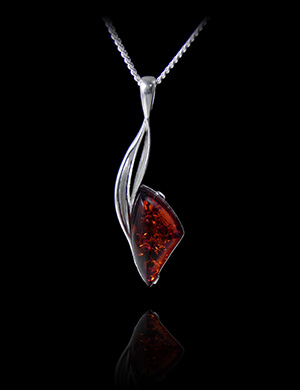 Pendentif en argent effilé et ajouré, très élégant, beau volume d'ambre couleur cognac,...