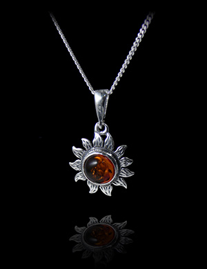 Pendentif d'un soleil en argent finement ciselé, serti d'ambre véritable en volume au centre,...
