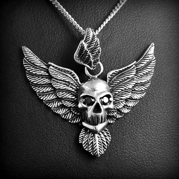 Pendentif crâne avec  yeux en zirconium noir  et deux belles ailes de chaque cotés en argent,...