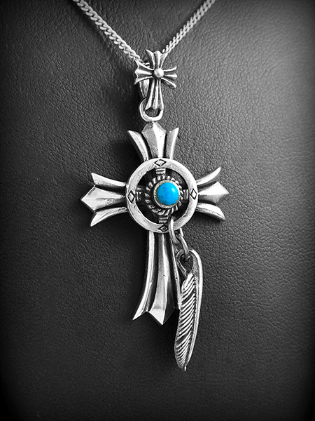 Pendentif en argent d'une croix en volume avec une petite pierre de turquoise au centre et d'une...