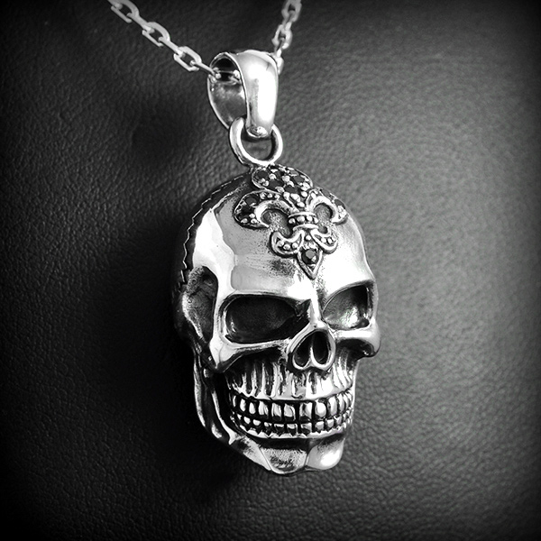 Pendentif en argent d'une belle tête de mort en volume ornée d'une fleur de lys et zirconiums...