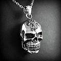 Pendentif en argent d'une belle tête de mort en volume ornée d'une fleur de lys et zirconiums...